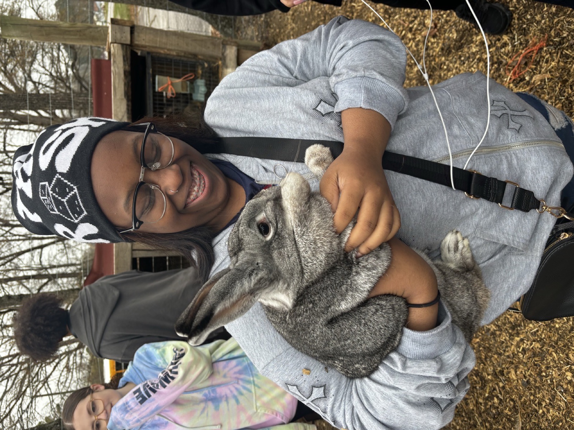 A grower smiling while caring for a rabbit at the Oasis Youth Farm